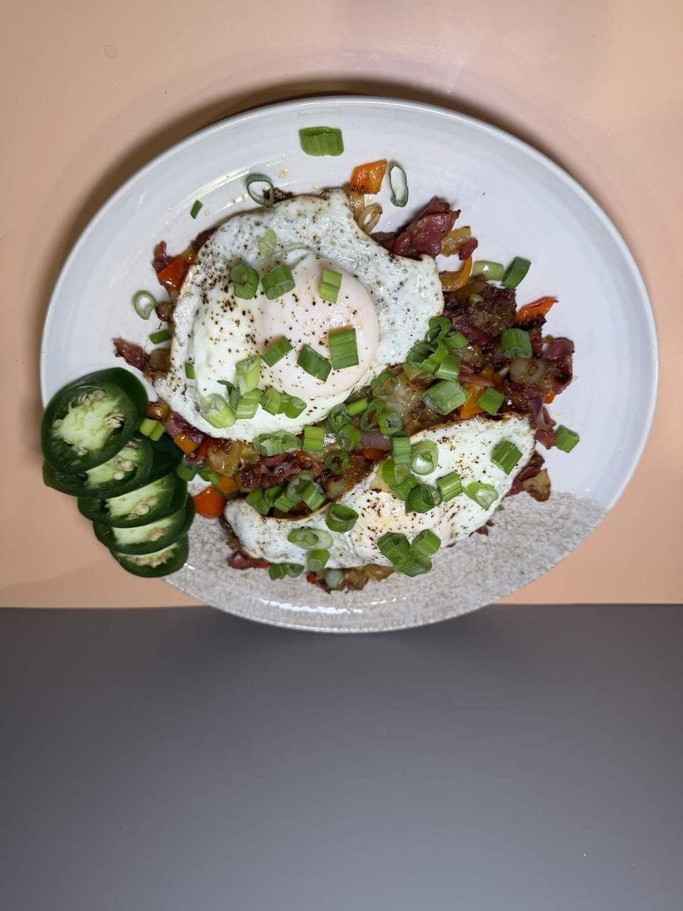 Breakfast Hash at Toasted Cafe in Montrose — Gold potatoes, red onion, green onion, colored bell pepper, cheese, choice of meat, eggs, jalapeño, house seasoning.