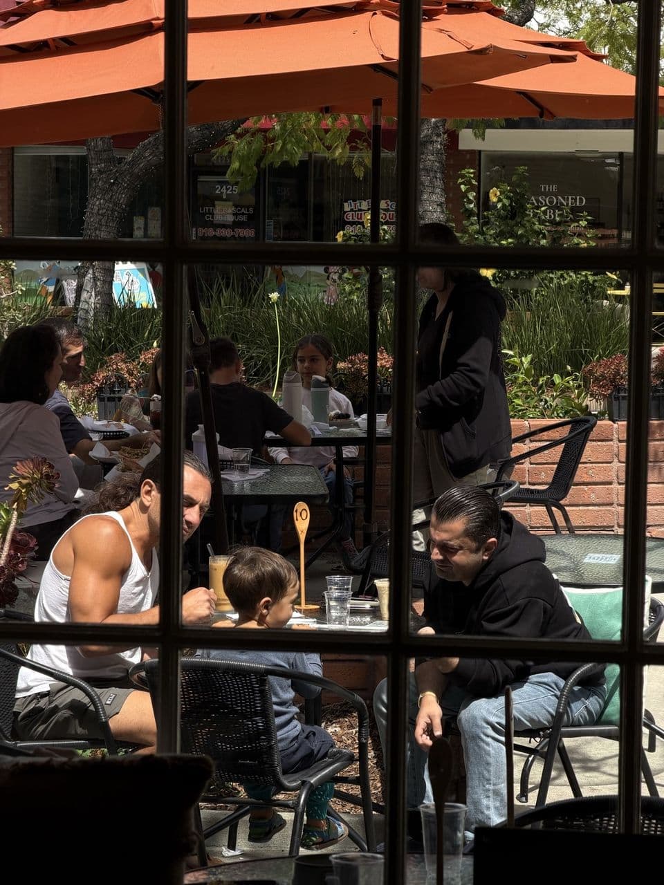 Guests dining on the patio at Toasted Cafe under orange umbrellas on Honolulu Avenue