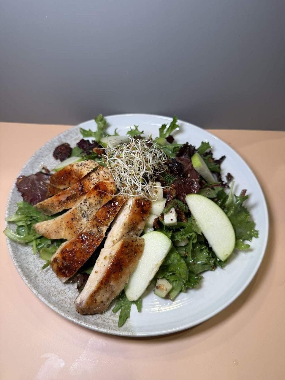Chicken Garden Salad at Toasted Cafe in Montrose — Fresh spring mix, grilled chicken breast, crisp apple, dried cranberries, candied pumpkin seeds & pecans, alfalfa sprouts, light pear vinaigrette.