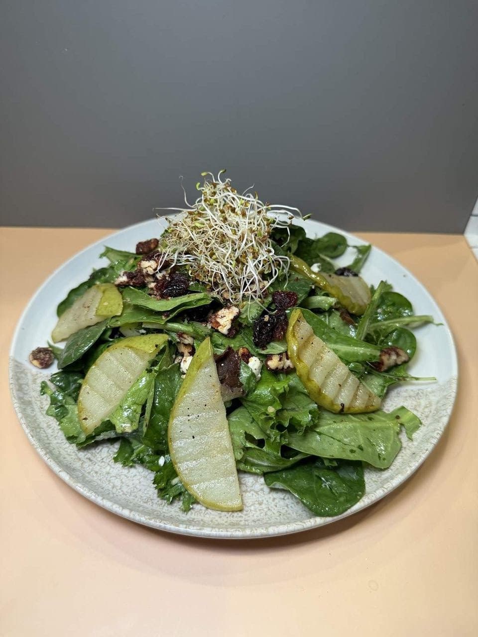 Pear & Greens Salad at Toasted Cafe in Montrose — Fresh spring mix, candied pecans and pumpkin seeds, goat cheese, caramelized pears, alfalfa sprouts, olive oil, pear vinaigrette.