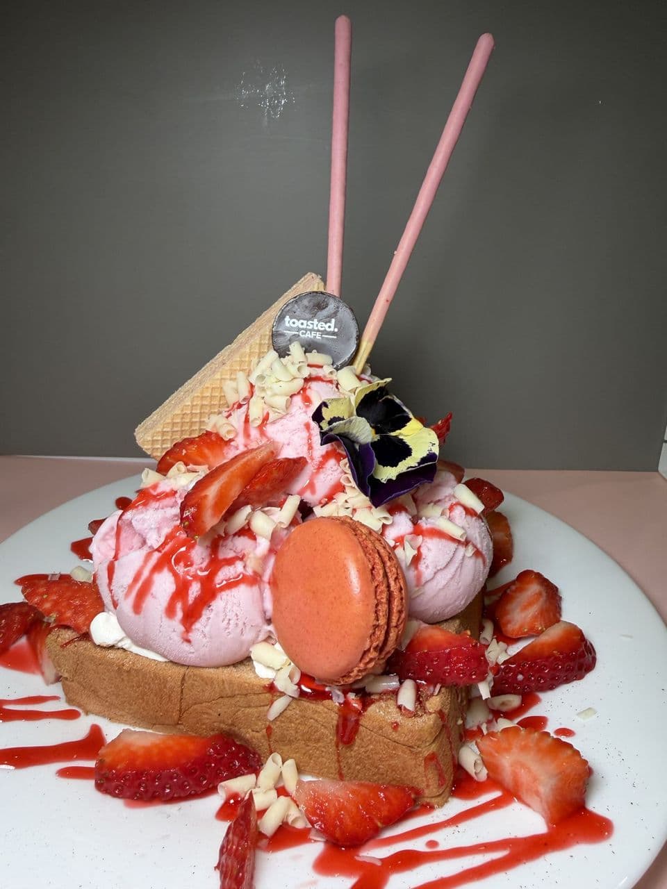 Strawberry Delight at Toasted Cafe in Montrose — Strawberry ice cream, strawberries, white chocolate curls, strawberry glaze, macaron, honey, whip cream.