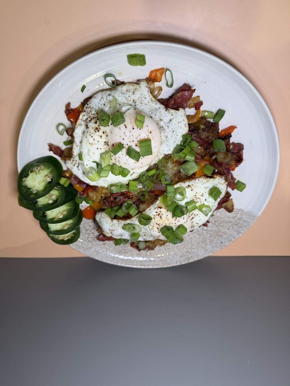 Breakfast Hash at Toasted Cafe in Montrose — Gold potatoes, red onion, green onion, colored bell pepper, cheese, choice of meat, eggs, jalapeño, house seasoning.