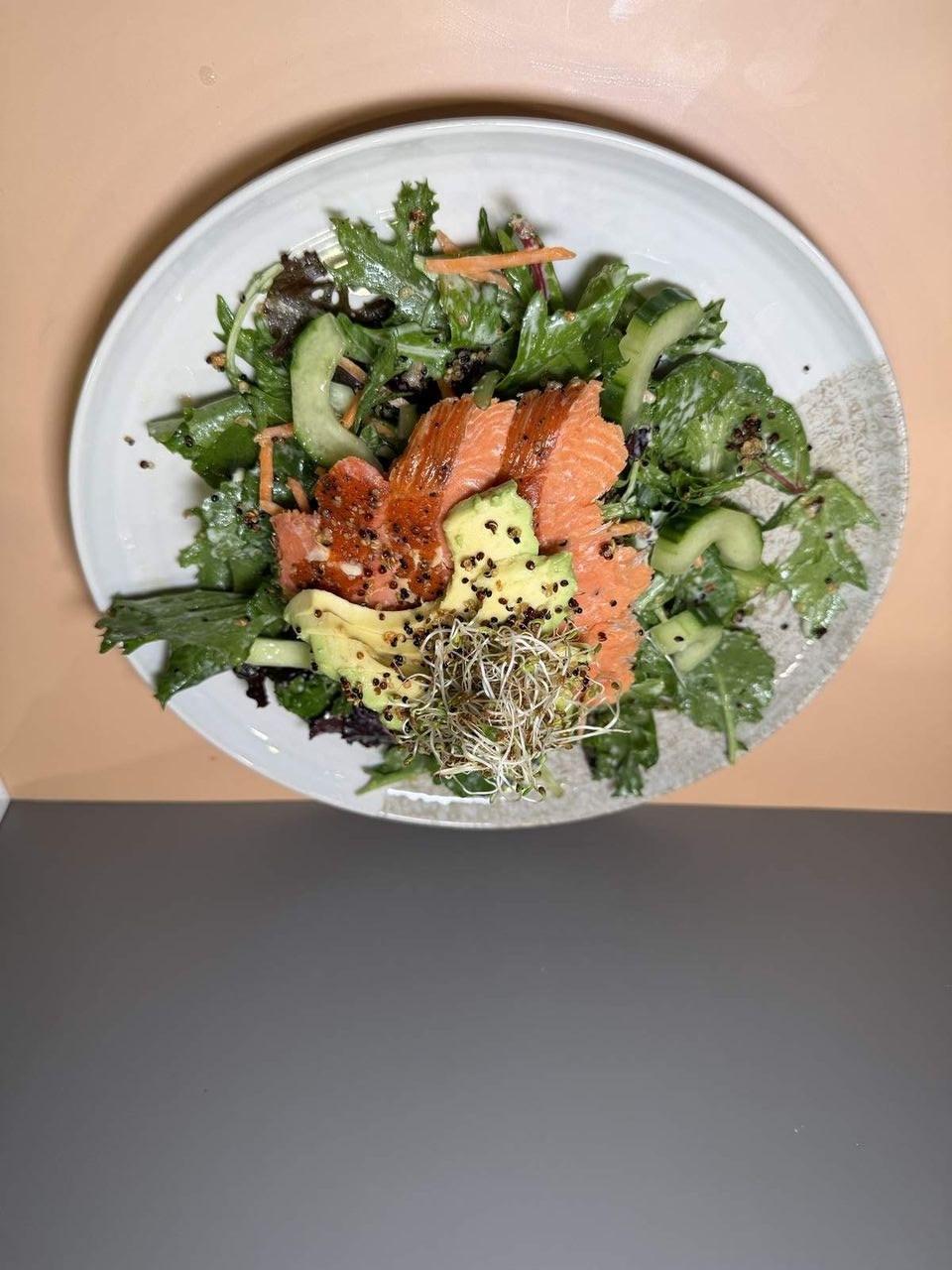 Quinoa Salmon Salad at Toasted Cafe in Montrose — Fresh spring mix, crispy quinoa, cucumber, carrots, avocado, salmon, house dressing.